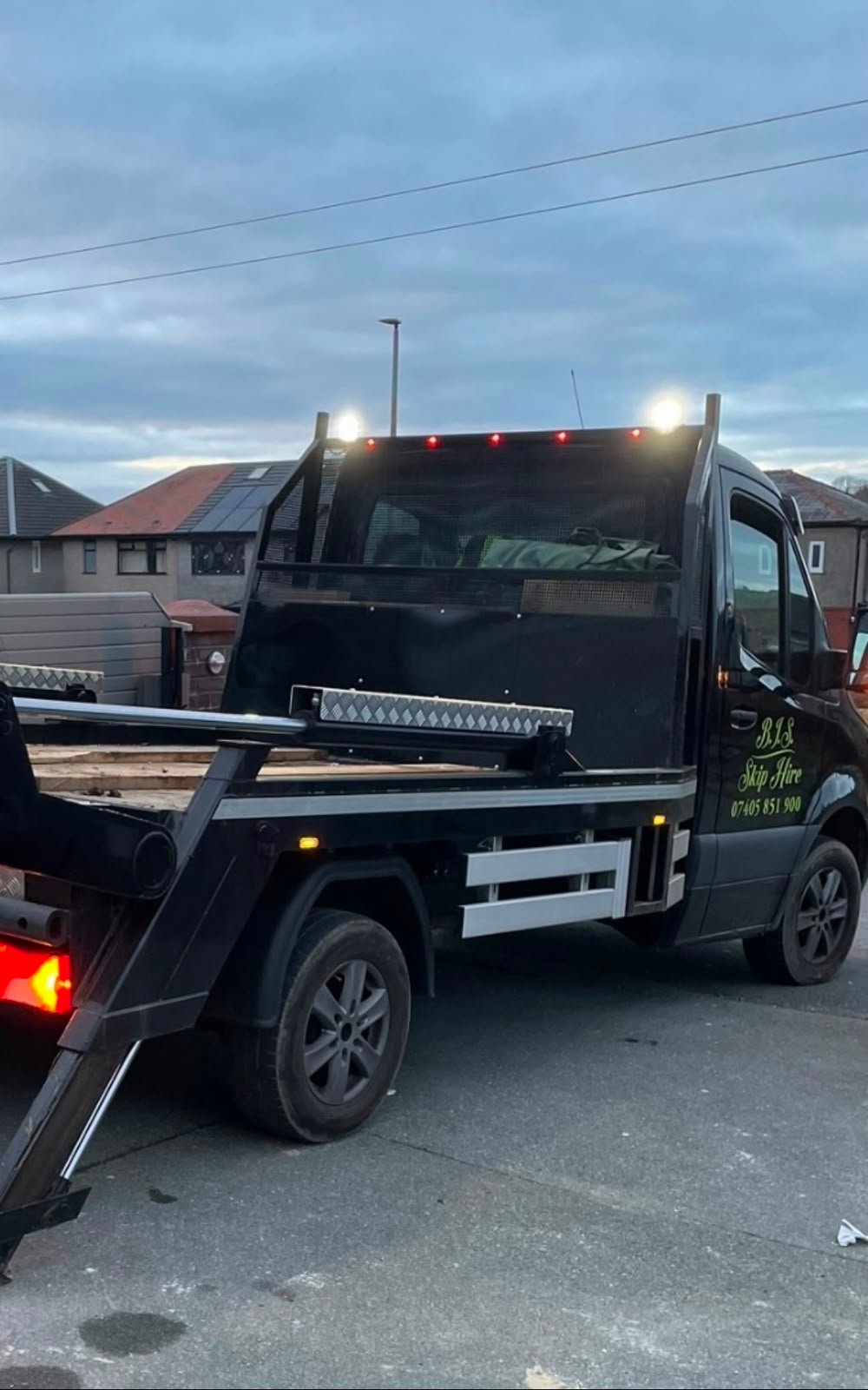 BIS Skip Hire branded flatbed truck delivering a skip in Lancashire